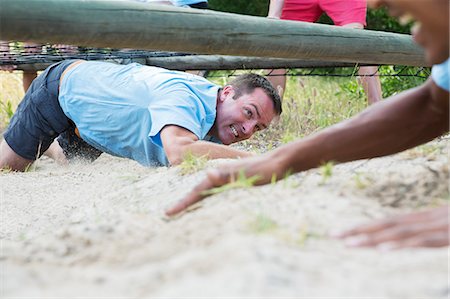 Determined man crawling under net on boot camp obstacle course Photographie de stock - Premium Libres de Droits, Code: 6113-08088098