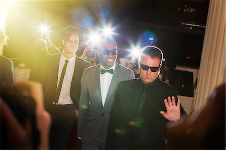 simsearch:693-06379562,k - Bodyguard escorting celebrities arriving at event and being photographed by paparazzi Stock Photo - Premium Royalty-Free, Code: 6113-08088169