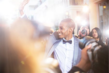 personas prominentes - Smiling celebrity waving to paparazzi photographers at event Foto de stock - Sin royalties Premium, Código: 6113-08088197