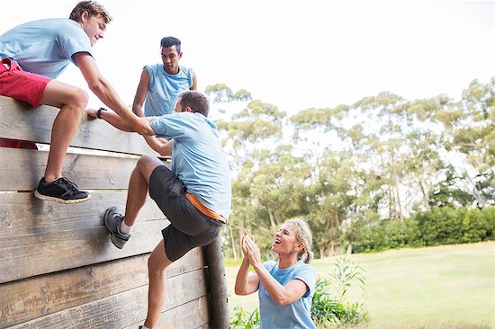 Teammates helping man over wall on boot camp obstacle course Foto de stock - Sin royalties Premium, Código de la imagen: 6113-08088123