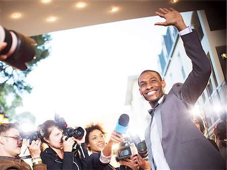 paparazzi taking pictures to celebrities - Waving celebrity being interviewed and photographed by paparazzi at event Stock Photo - Premium Royalty-Free, Code: 6113-08088203