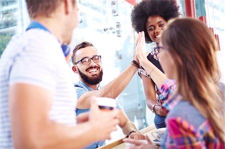 people hanging out - Friends high fiving in cafe Stock Photo - Premium Royalty-Free, Code: 6113-08088472