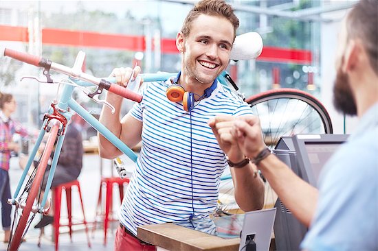 Man with bicycle fist bumping worker in cafe Stock Photo - Premium Royalty-Free, Image code: 6113-08088479