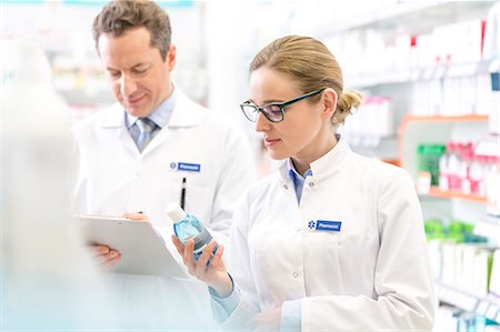 Pharmacist reading label on bottle in pharmacy Stock Photo - Premium Royalty-Free, Code: 6113-08088402