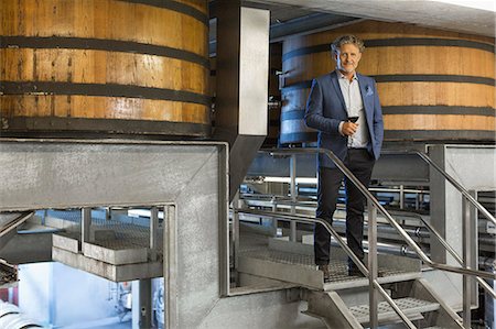 Portrait confident vintner with red wine on platform in winery cellar Photographie de stock - Premium Libres de Droits, Code: 6113-08171148