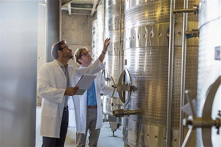 Vintners in lab coats checking vats in winery cellar Stock Photo - Premium Royalty-Free, Code: 6113-08171112