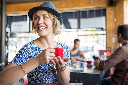 Smiling woman drinking coffee looking over shoulder in cafe Photographie de stock - Premium Libres de Droits, Code: 6113-08171257