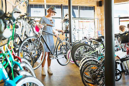 simsearch:6113-08171368,k - Woman selecting bicycle from rack in bicycle shop Foto de stock - Royalty Free Premium, Número: 6113-08171261