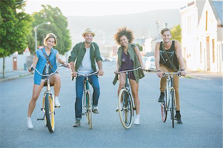 simsearch:6113-08171306,k - Portrait smiling friends sitting on bicycles on road Fotografie stock - Premium Royalty-Free, Codice: 6113-08171268