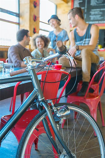 Friends hanging out at cafe behind bicycle Stock Photo - Premium Royalty-Free, Image code: 6113-08171271