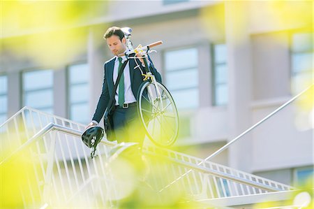 security - Businessman in suit carrying bicycle in city Stock Photo - Premium Royalty-Free, Code: 6113-08171298