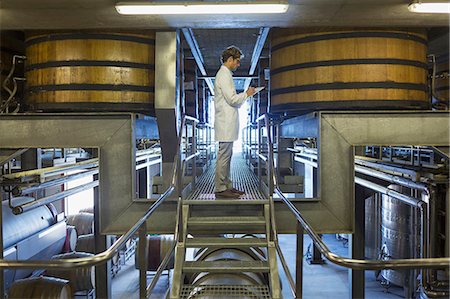 Vintner in lab coat on platform in winery cellar Stock Photo - Premium Royalty-Free, Code: 6113-08171208