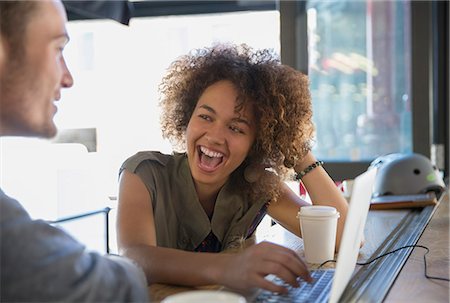 Enthusiastic woman laughing at laptop in cafe Stock Photo - Premium Royalty-Free, Code: 6113-08171348
