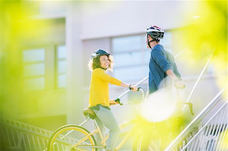 person riding bike - Man and woman with helmets on bicycles talking Stock Photo - Premium Royalty-Free, Code: 6113-08171306
