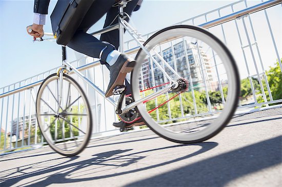 Low section businessman in suit riding bicycle on sunny urban sidewalk Foto de stock - Sin royalties Premium, Código de la imagen: 6113-08171322