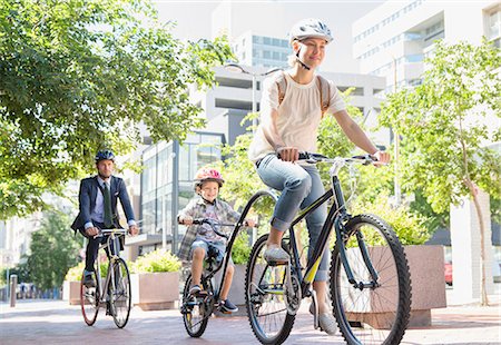 simsearch:6113-08171264,k - Mother and son in helmets riding tandem bicycle in urban park Stock Photo - Premium Royalty-Free, Code: 6113-08171327