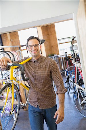 simsearch:6113-08171368,k - Portrait smiling man with eyeglasses carrying bicycle in bicycle shop Foto de stock - Royalty Free Premium, Número: 6113-08171328
