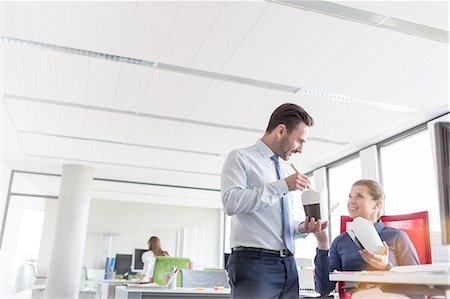 eating takeout - Businessman and businesswoman eating Chinese takeout with chopsticks in office Stock Photo - Premium Royalty-Free, Code: 6113-08171461