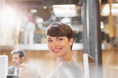 simsearch:6113-08105408,k - Smiling businesswoman drinking coffee in office Foto de stock - Royalty Free Premium, Número: 6113-08184271