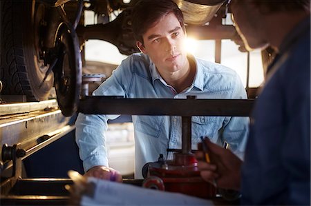 Mechanic and customer talking under car in auto repair shop Stock Photo - Premium Royalty-Free, Code: 6113-08184348
