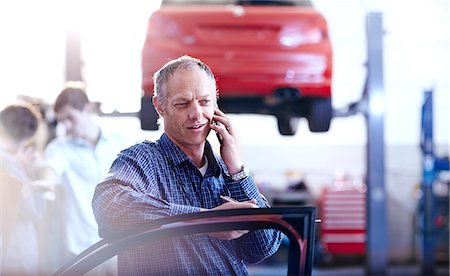 simsearch:6113-08184367,k - Man talking on cell phone in auto repair shop Photographie de stock - Premium Libres de Droits, Code: 6113-08184367