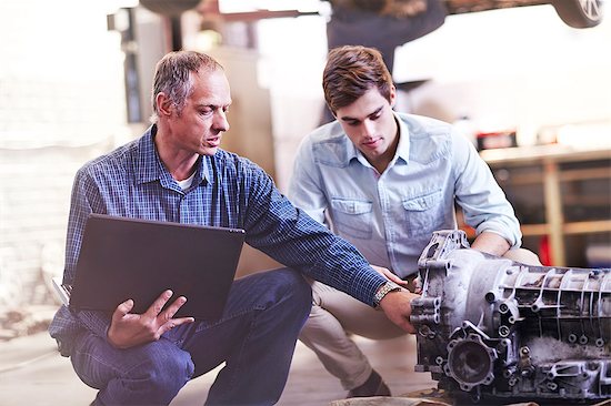 Mechanic with laptop and customer examining engine in auto repair shop Stock Photo - Premium Royalty-Free, Image code: 6113-08184376