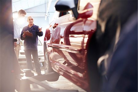 Mechanic with clipboard talking to customer in auto repair shop Foto de stock - Sin royalties Premium, Código: 6113-08184383