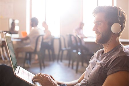 Casual businessman wearing headphones and working at laptop in office Photographie de stock - Premium Libres de Droits, Code: 6113-08105382