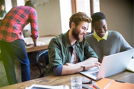 simsearch:6113-07731430,k - Smiling casual business people working at laptop in office Stock Photo - Premium Royalty-Free, Code: 6113-08105388