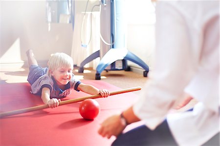 simsearch:6113-08105459,k - Physical therapist guiding boy rolling ball with stick Stock Photo - Premium Royalty-Free, Code: 6113-08105464