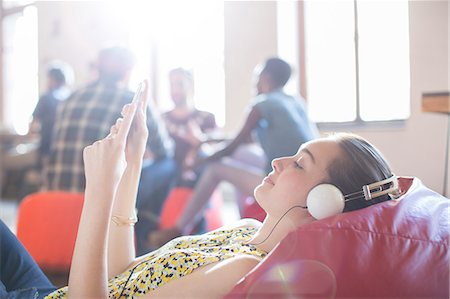 Casual businesswoman relaxing with headphones and digital tablet on bean bag chair Photographie de stock - Premium Libres de Droits, Code: 6113-08105421