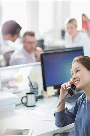 Smiling businesswoman talking on telephone at desk in office Photographie de stock - Premium Libres de Droits, Code: 6113-08220297