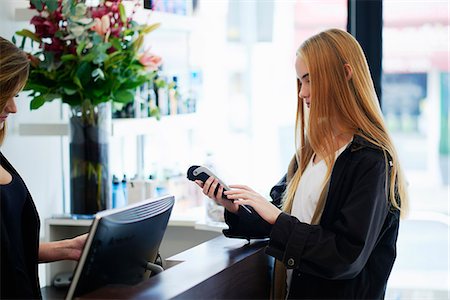 simsearch:6113-08220391,k - Woman paying with credit card reader at counter in hair salon Fotografie stock - Premium Royalty-Free, Codice: 6113-08220392