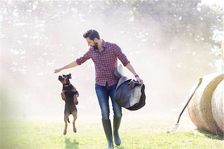 Man with saddle walking with jumping dog Photographie de stock - Premium Libres de Droits, Code: 6113-08220394