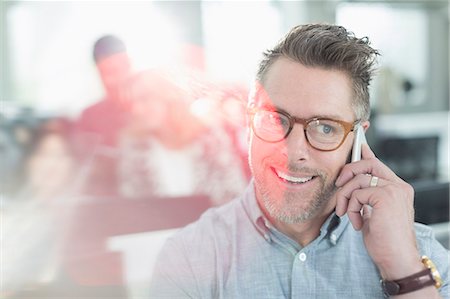 simsearch:6113-08986035,k - Smiling businessman talking on cell phone in office Stock Photo - Premium Royalty-Free, Code: 6113-08220322
