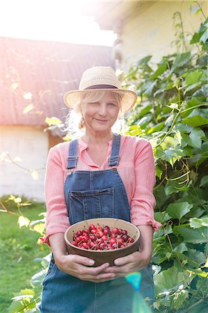 Portrait smiling woman in overalls holding harvested cherries Photographie de stock - Premium Libres de Droits, Code: 6113-08220459