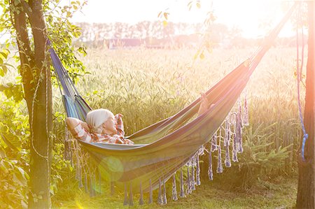 resting woman - Serene woman napping in hammock next to sunny rural wheat field Stock Photo - Premium Royalty-Free, Code: 6113-08220463