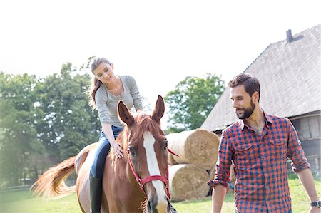 equestrian - Man leading woman horseback riding in rural pasture Stock Photo - Premium Royalty-Free, Code: 6113-08220413