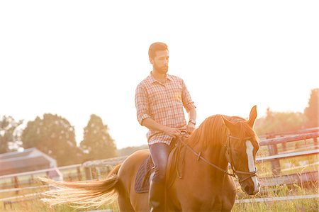 simsearch:6113-08220442,k - Man horseback riding in sunny rural pasture Foto de stock - Sin royalties Premium, Código: 6113-08220410