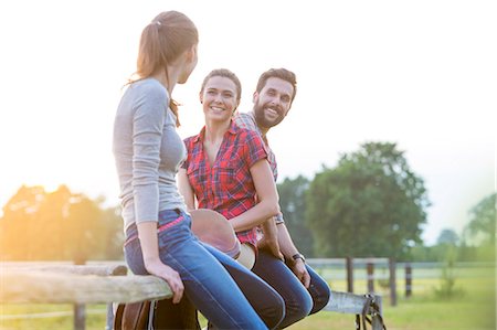 simsearch:6113-08220442,k - Smiling friends sitting on rural fence Foto de stock - Sin royalties Premium, Código: 6113-08220422