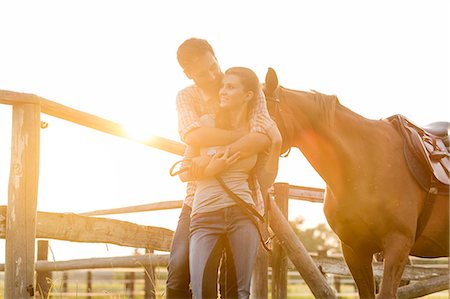 standing at sunset - Couple with horse hugging in sunny rural pasture Stock Photo - Premium Royalty-Free, Code: 6113-08220427