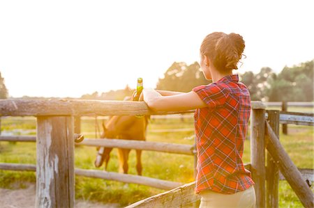 ranch - Woman drinking beer and watching horse in rural pasture Photographie de stock - Premium Libres de Droits, Code: 6113-08220436