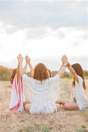 Boho women sitting in circle with arms raised and connected in rural field Stock Photo - Premium Royalty-Free, Code: 6113-08220543