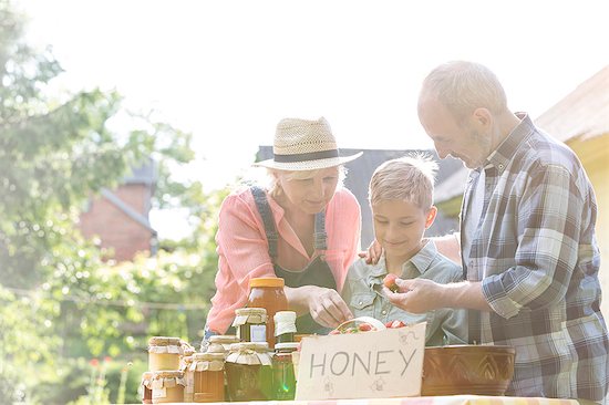 Grandparents and grandson selling honey at farmer's market stall Stock Photo - Premium Royalty-Free, Image code: 6113-08220527