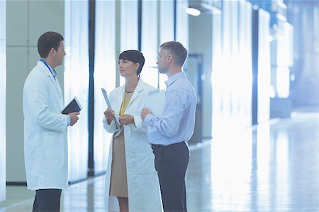 Scientists and businessman talking in factory corridor Stock Photo - Premium Royalty-Free, Code: 6113-08393578