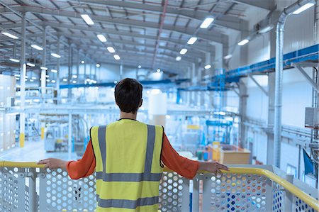 Worker in reflective clothing on platform looking out over factory Stock Photo - Premium Royalty-Free, Code: 6113-08393676