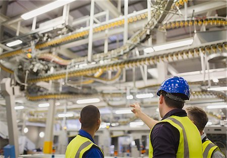 Workers discussing winding printing press conveyor belts overhead Photographie de stock - Premium Libres de Droits, Code: 6113-08393603