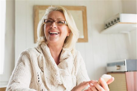 simsearch:6102-08271801,k - Smiling senior woman in sweater texting with cell phone in kitchen Stockbilder - Premium RF Lizenzfrei, Bildnummer: 6113-08393744