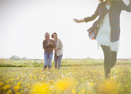 energetic family field - Women watching girl run in sunny meadow with wildflowers Stock Photo - Premium Royalty-Free, Code: 6113-08393791