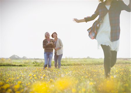 running watch - Women watching girl run in sunny meadow with wildflowers Stock Photo - Premium Royalty-Free, Code: 6113-08393791